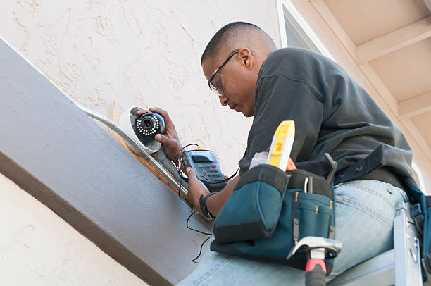 Technician installing a security camera on a building exterior